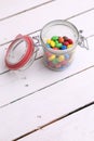 Vertical high angle shot of a glass jar filled with colorful chocolate balls on a wooden table Royalty Free Stock Photo