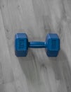 Vertical high angle shot of a 4KG blue dumbbell on the wooden floor