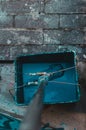 Vertical high angle shot of a mop put in a bucket of blue paint on a stone surface