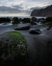 Vertical high angle shot of the mossy stones in the beach on a dark cloudy day Royalty Free Stock Photo