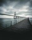 Vertical high angle shot of a wooden bridge over the sea under the dark cloudy sky Royalty Free Stock Photo