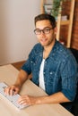 Vertical high-angle view of positive young freelance programmer male in stylish glasses working on desktop computer Royalty Free Stock Photo