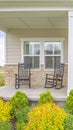 Vertical Home facade with stairs leading to porch with pillars and gray door with wreath