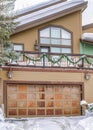 Vertical Home with snowy yard and driveway in front of front door and metal garage door