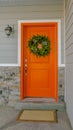 Vertical Home with a welcoming wreath hanging on the orange front door