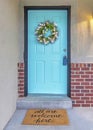 Vertical House exterior with red bricks and cyan front door with lockbox and wreath