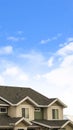 Vertical House exterior with view of the dark pitched roof against a cloudy blue sky