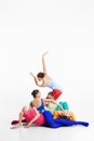 Vertical image of artisitc young girls, ballet dancers in multicolored bright clothes making performance, dancing