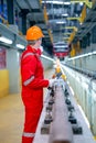 Vertical image and back of professional technician worker with safety uniform point to the electrical or sky train in factory