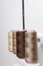 Vertical image.Beige colors of spools of thread, overlock machine for sewing against white background