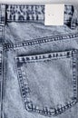 Vertical image of blue jeans and empty paper tag on it. Blank tag for price or clothing size Royalty Free Stock Photo