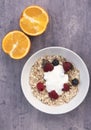 Vertical image of a bowl of Muesli with two orange halves