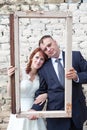 Vertical image of bride and groom looking through portrait frame