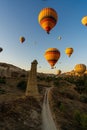 Vertical image of bunch of colorful hot air balloon flying early morning in Cappadocia, Turkey against typical rock formation due