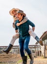 Vertical image of Caucasian man and woman farmer enjoy with woman riding on the back of man and go around the area of their farm