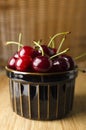 Vertical image.Ceramic brown bowl full of ripe and juicy cherries on the wooden board against wicker background