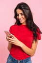 Vertical image of cheerful brunette woman using her smartphone