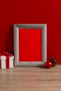 Vertical image of chrsitmas decorations and wooden frame with copy space on red background