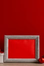 Vertical image of chrsitmas decorations and wooden frame with copy space on red background