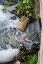 Vertical image, dirty sewage water , human trash flowing in to a small creek.