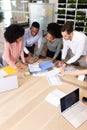 Vertical image of diverse female and male businesspeople talking and working in office