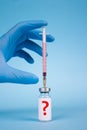 Vertical image, doctor hand injecting with vial dose of vaccine or another medicine with syringe against blue background with copy