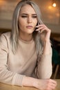 Vertical of dramatic surprised blond woman, staring, talking phone, cafe, sitting table. Business problem, remote work Royalty Free Stock Photo