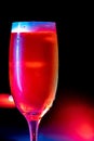 Vertical image of a full glass of Champaign in the dark background with red and blue lights