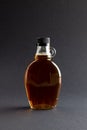 Vertical image of glass bottle of maple syrup on dark grey background, with copy space Royalty Free Stock Photo