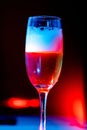 Vertical image of a glass of Champaign in the dark background with red and blue lights