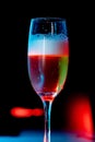 Vertical image of a glass of Champaign in the dark background with red and blue lights