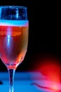 Vertical image of a glass of Champaign in the dark background with red and blue lights