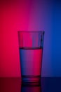 Vertical image glass of water on blue pink background