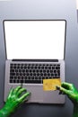 Vertical image of green monster hands with credit card on laptop with copy space on grey background Royalty Free Stock Photo