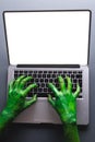 Vertical image of green monster hands writing on laptop with copy space on grey background Royalty Free Stock Photo