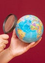 Vertical image of a hand holding a magnifying glass over an world globe Royalty Free Stock Photo