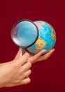 Vertical image of a hand holding a magnifying glass over an world globe Royalty Free Stock Photo