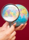 Vertical image of a hand holding a magnifying glass over an world globe Royalty Free Stock Photo