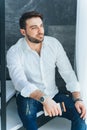 Vertical image of handsome businessman with blue eyes, look away, sitting on stairs. Telecommuting, consulting business Royalty Free Stock Photo