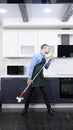 Vertical image. handsome man in tie and apron mops the floor in the kitchen