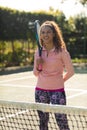 Vertical image of happy biracial girl with tennis racket looking at camera in court Royalty Free Stock Photo