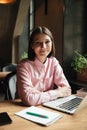 Vertical image of Happy brunette woman sitting by the table