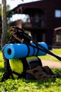 Vertical image of hiking poles, shoes and backpack with mat over log cabin on sunny day Royalty Free Stock Photo