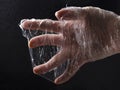 Human hand in the plastic sheeting against black background.Concept of global environmental pollution
