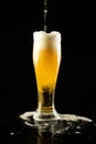 Vertical image of lager beer dripping into overflowing pint glass on black, with copy space