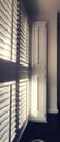 Vertical image of light shining through window with plantation shutters Royalty Free Stock Photo