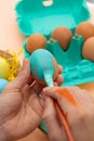 Vertical image of male hands painting an Easter egg blue Royalty Free Stock Photo
