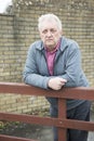 Vertical image of a mature man leaning against a wooden gate Royalty Free Stock Photo