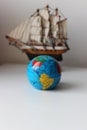 Vertical Image Of Miniature Globe In Front Of Mast Ship Model Isolated On White Backdrop Royalty Free Stock Photo