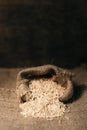 Vertical image of a natural unpolished brown rice in burlap sack over dark background